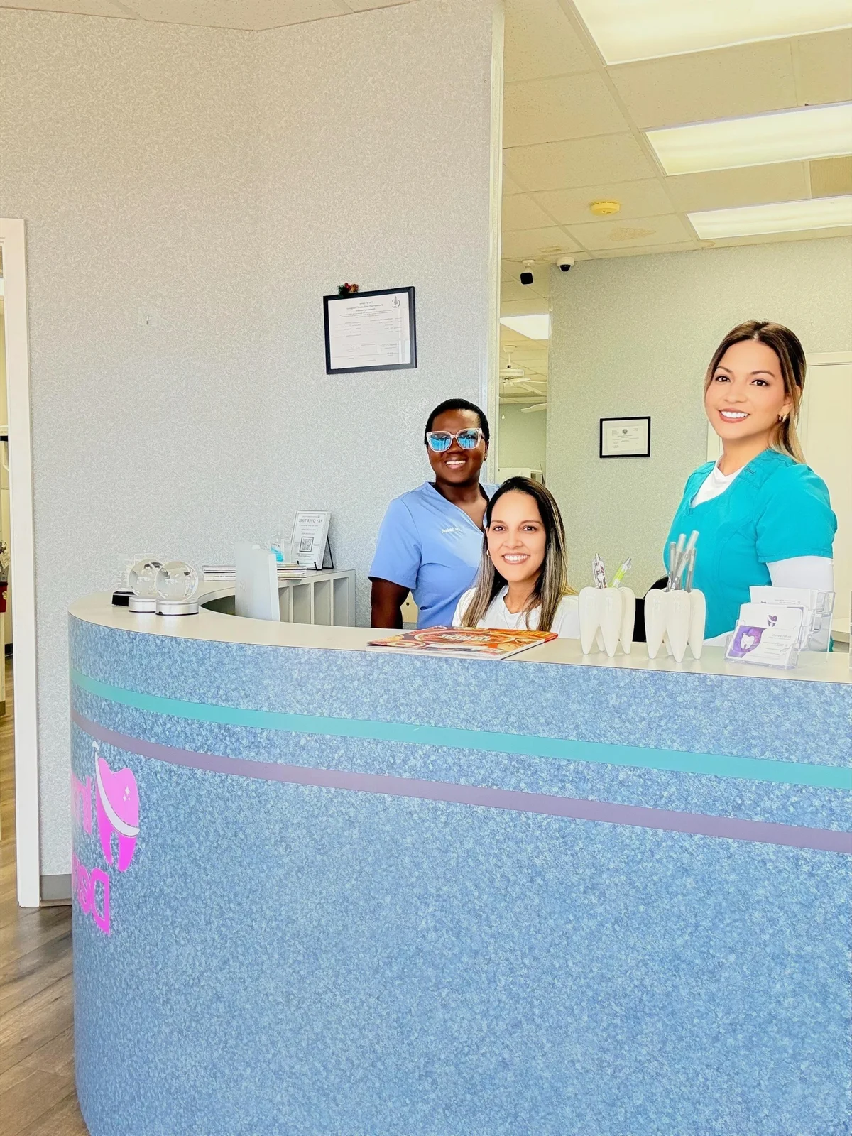 Three team members behind the Imma Dental reception desk