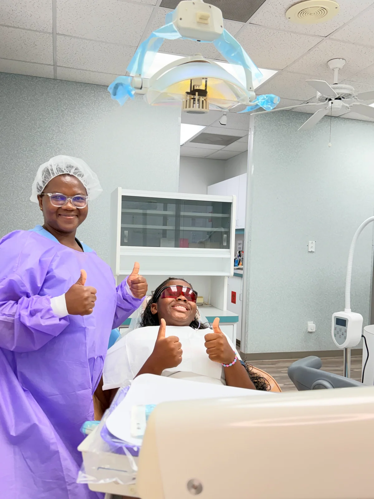Dental professional beside a smiling patient in a treatment chair