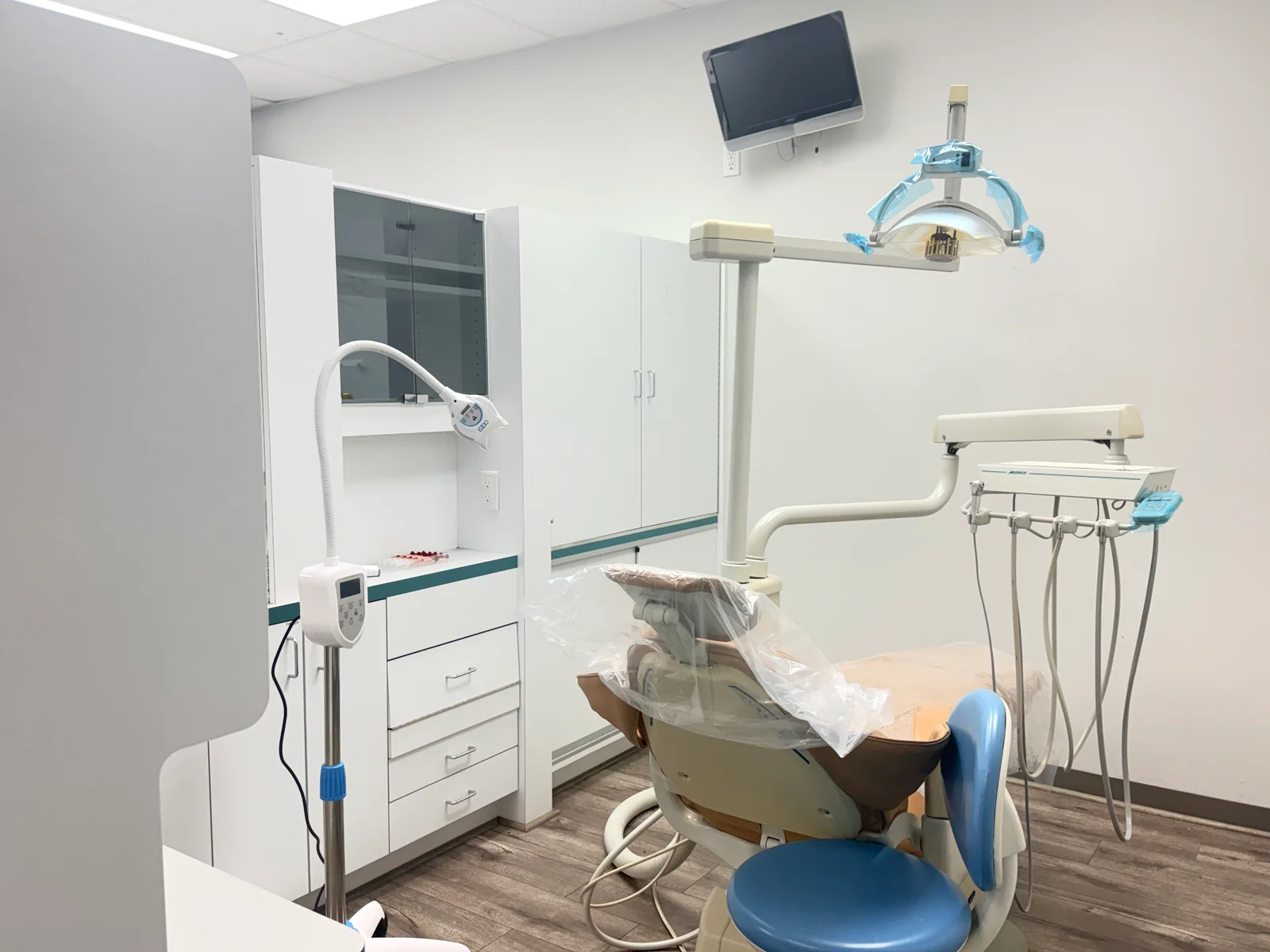 Dental treatment room with a chair, overhead light, and monitor